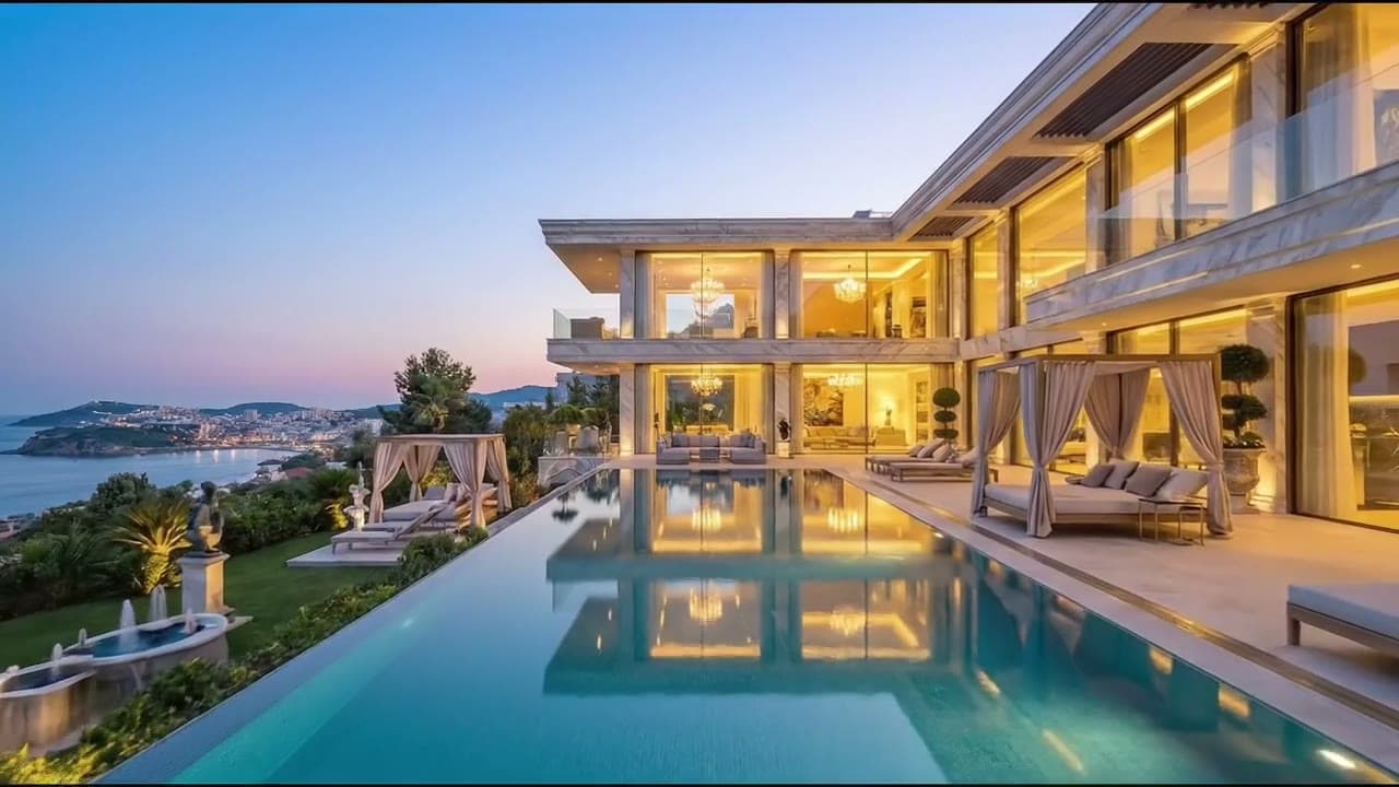 A lit villa above an infinity pool at dusk